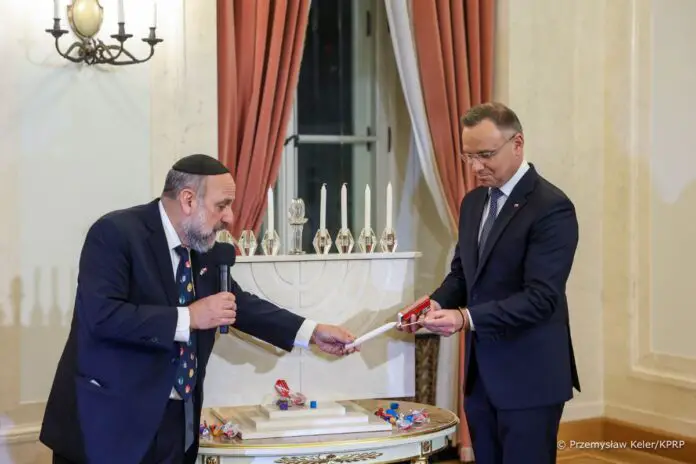 Prezydent Andrzej Duda zapala świecę chanukową.