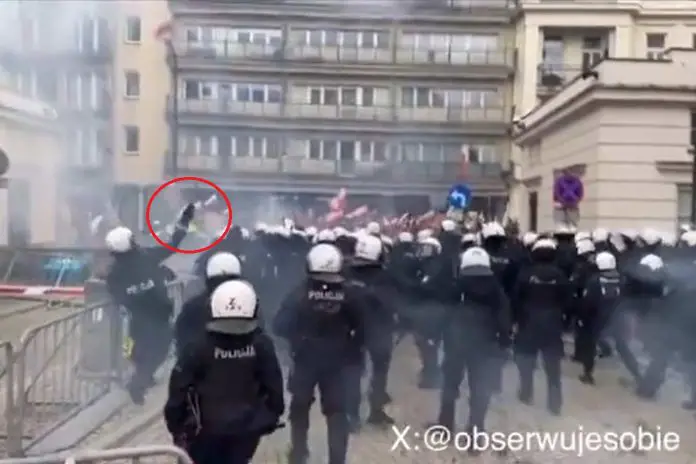 Policjant rzucający (najprawdopodobniej) kostką brukową w protestujących rolników. Warszawa, 6 marca 2024 r.