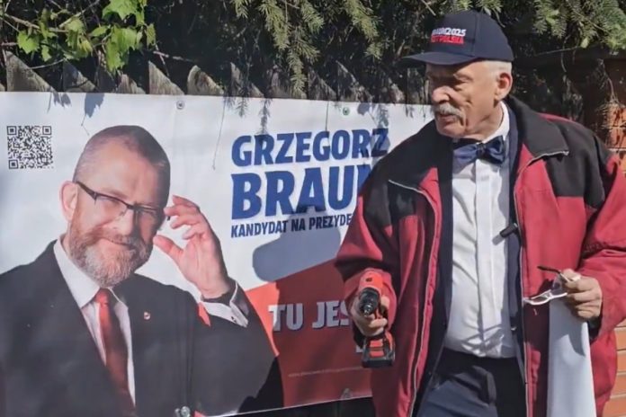 Janusz Korwin-Mikke wieszający nowy banner kandydata na prezydenta Polski Grzegorz Brauna. Foto: print screen X @JkmMikke