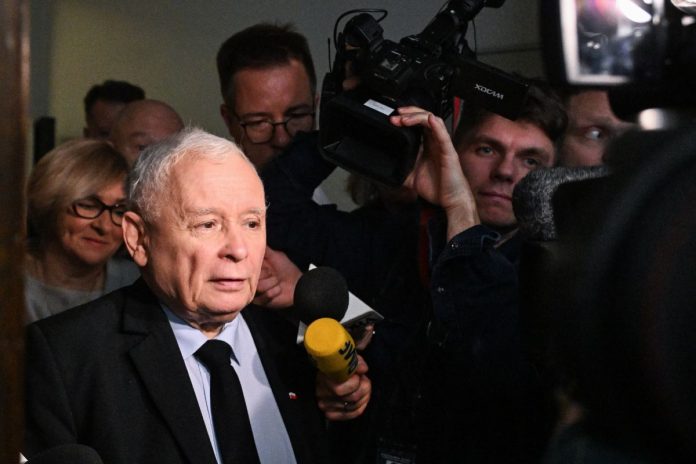 Jarosław Kaczyński otoczony przez dziennikarzy na korytarzu sejmowym.