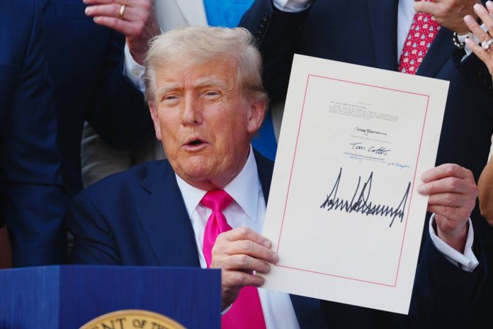 Donald Trump pokazuje podpis po ustawą. Foto; PAP/EPA