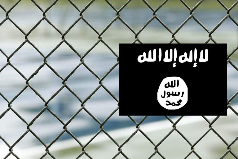 Płot oraz flaga tzw. Państwa islamskiego. Obrazek ilustracyjny.