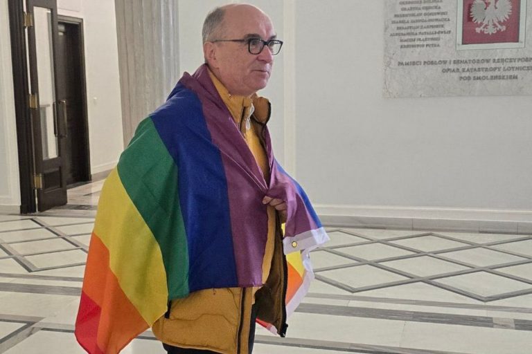 Włodzimierz Czarzasty owinięty flagą LGBT.