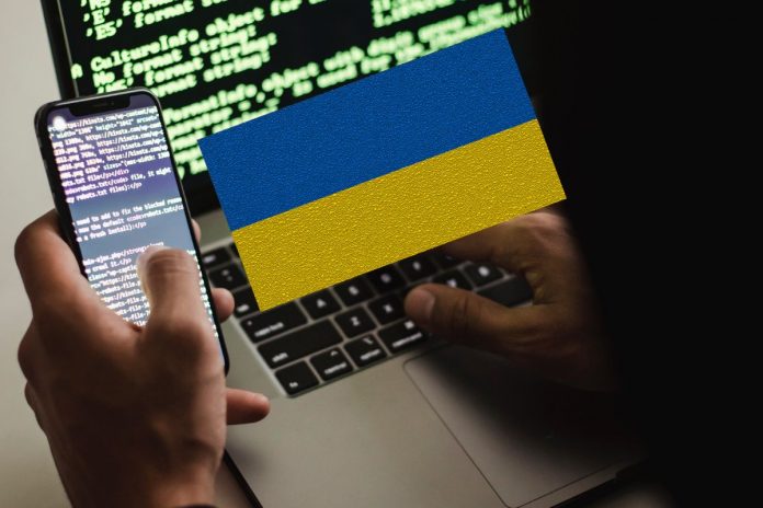 Komputer, smartfon, haker, ukraińska flaga
